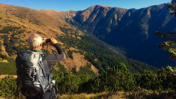 Mann fotografiert mit seinem Handy das Gebirge 