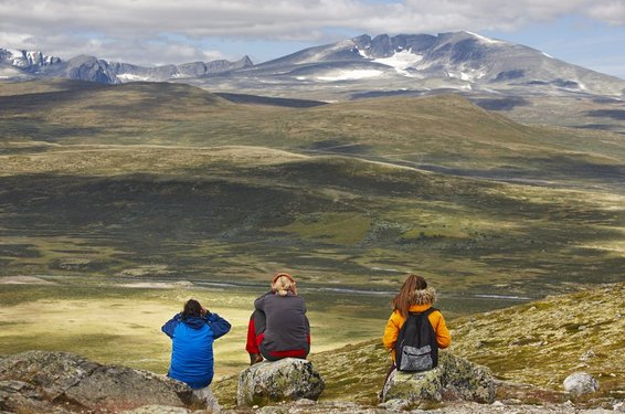 Drei junge Frauen erholen sich von einer Wanderung mit einem schönen Ausblick auf Dovrefjell in Norwegen.