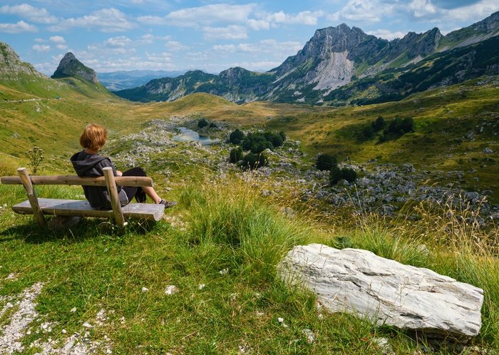 Eine Frau sitzt auf einer Parkbank und genießt die Aussicht im Durmitor Nationalpark in Montenegro.