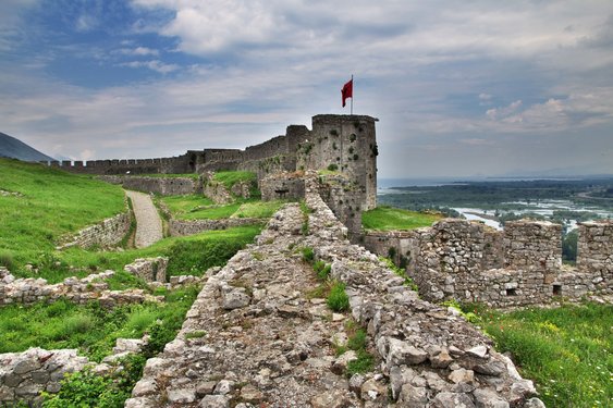 Man sieht die Ruinen einer Festung in deren Hintergrund sich die Sicht bis zum Meer erstreckt.