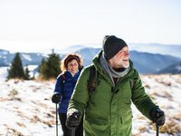 Winterwandern hält fit Zwei ältere Wanderer mit Winterausrüstung