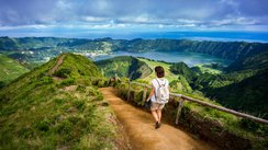 Eine Frau läuft einen Fußweg talwärts Richtung Sete Cidades auf São Miguel.