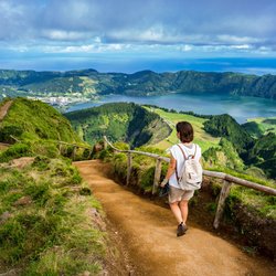 Eine Frau läuft einen Fußweg talwärts Richtung Sete Cidades auf São Miguel.