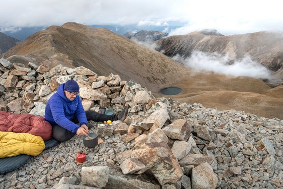 Essen während der Wanderung Ein Wanderer bereitet in den Bergen eine Mahlzeit zu