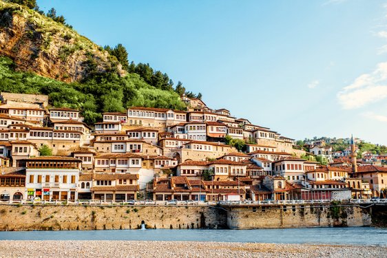 Entlang eines Hangs der sich von rechts unten nach links oben erhebt erstreckt sich die Stadt Berat mit ihrer osmanischen Architektur.