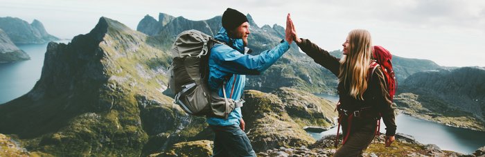 Ein Pärchen gibt sich ein "High Five" nach einer Bergwanderung.