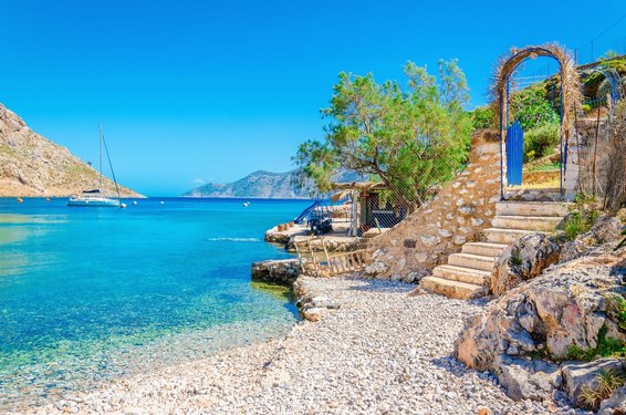 Kalymnos: Nach dem Wandern lockt das Meer Rechts erstreckt sich der Zugang zu einer Bucht mit Kiesstrand, links leuchtet das Meer azurblau.