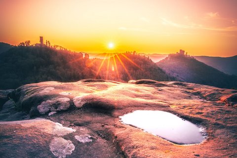 Die Sandsteinklippen des Pfälzerwalds sind vom Licht der untergehenden Sonne orange gefärbt.