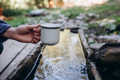 Eine Frau füllt ihre Wassertasse mit frischem Quellwasser.