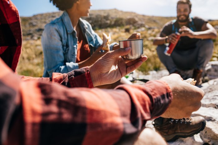 Eine Wandergruppe macht eine kurze Wanderpause und stärkt sich.