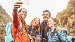 Eine Gruppe bestehend aus zwei Männern und zwei Frauen nehmen lachend ein Selfie auf.