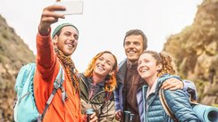 Eine Gruppe bestehend aus zwei Männern und zwei Frauen nehmen lachend ein Selfie auf.