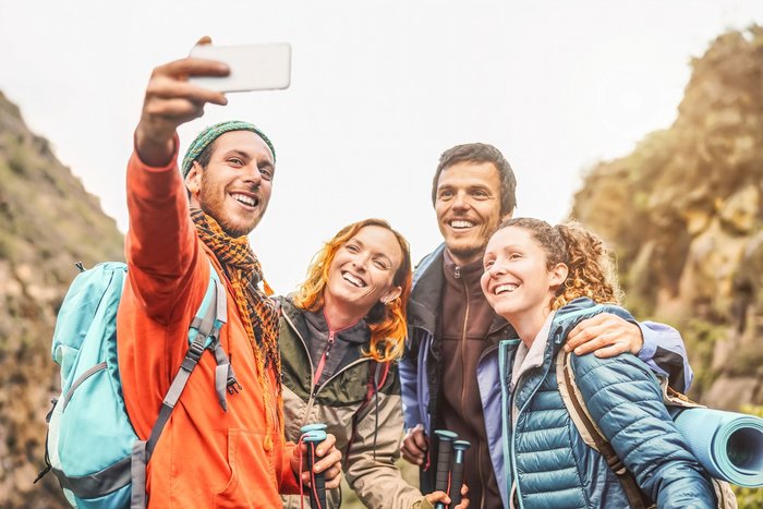 Eine Gruppe bestehend aus zwei Männern und zwei Frauen nehmen lachend ein Selfie auf.