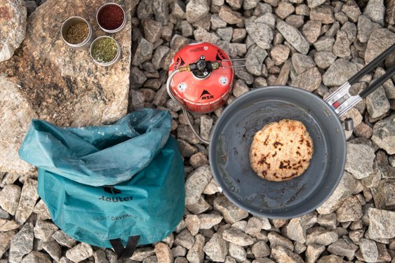 Ein Gaskocher, Ein Kochtopf und eine Tasche stehen auf dem Boden