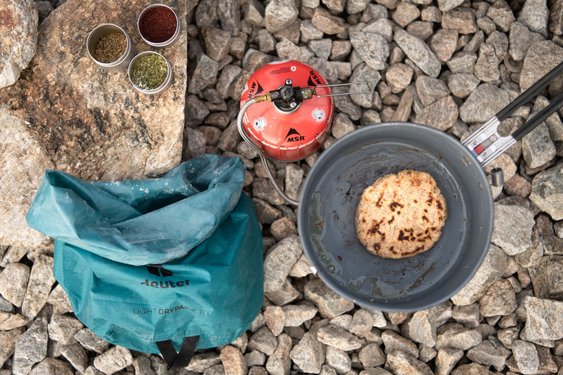 Kochequipment für die Wanderung Ein Gaskocher, Ein Kochtopf und eine Tasche stehen auf dem Boden