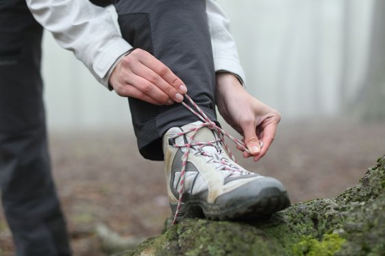 Ein Wanderer schnürt seinen Wanderstiefel