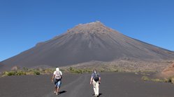 Zwei Wanderer laufen dem Vulkan Pico do Fogo auf der Kapverden-Insel Fogo entgegen.