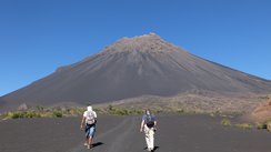 Zwei Wanderer laufen dem Vulkan Pico do Fogo auf der Kapverden-Insel Fogo entgegen.