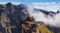 Wanderer belohnen sich auf dem Gipfel des Pico Ruivo mit einem spektakulären Ausblick über den Wolken.