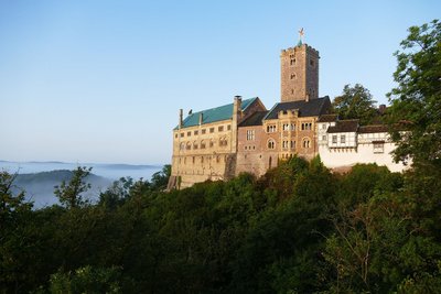 Die Wartburg thront hoch auf bewaldeten Hügeln.