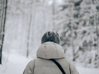 Warm angezogen beim Winterwandern Der Hinterkopf eines Wanderers, der im Schnee eine dicke Jacke und eine Mütze trägt