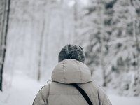 Der Hinterkopf eines Wanderers, der im Schnee eine dicke Jacke und eine Mütze trägt