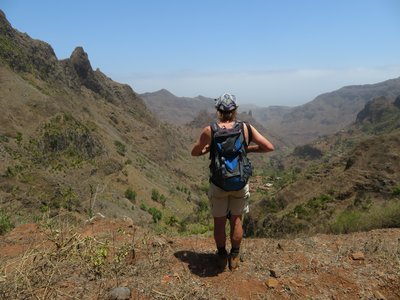 Eine Wanderin blickt über Gebirgszüge