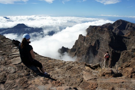 Zwei Wanderer schauen auf die wolkenverhangene Caldera de Taburiente auf La Palma.