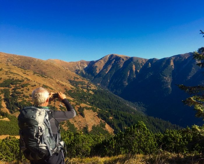 Mann fotografiert mit seinem Handy das Gebirge 