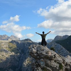 Ein Wanderer reckt die Arme bei einer Gipfelwanderung auf Mallorca.