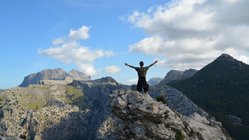 Ein Wanderer reckt die Arme bei einer Gipfelwanderung auf Mallorca.