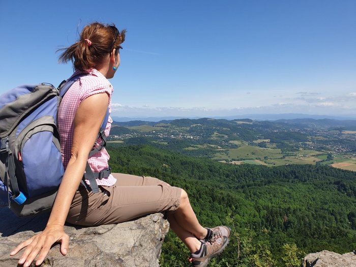 Frau schaut hoch vom Felsen über die Landschaft