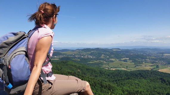 Frau schaut hoch vom Felsen über die Landschaft