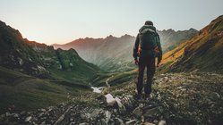 Ein Wanderer blickt in die Berge mit dem Rücken zur Kamera gekehrt