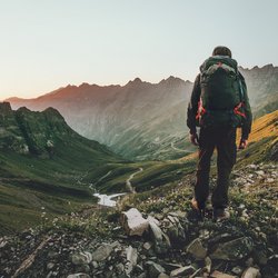 Ein Wanderer blickt in die Berge mit dem Rücken zur Kamera gekehrt